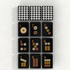 The image is a collage of nine black and white tiles, each featuring a unique design or pattern. The tiles are arranged in a grid format, with three tiles on the top row, three on the middle row, and three on the bottom row. The tiles display various shapes, such as circles, squares, and triangles, creating a visually interesting and diverse collection.