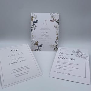 May include: Wedding invitation suite featuring three white cards with floral and botanical accents. The invitations include the names Nicola and Daymein, along with event details. The design is elegant and minimalist.