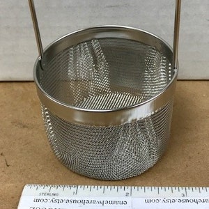 May include: A stainless steel mesh basket with a handle. The basket is cylindrical with a fine mesh design. A ruler is placed next to the basket. The text "ENAMEL WAREHOUSE" and "enamelwarehouse.etsy.com" is visible on the ruler.