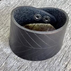 May include: Black leather cuff bracelet with a braided design and two silver snap closures.