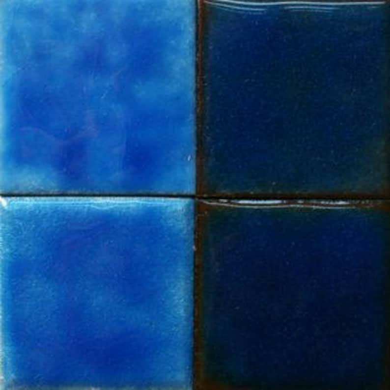 Puede incluir: Cuatro azulejos cuadrados de cer&aacute;mica en tonos azules. Los azulejos est&aacute;n esmaltados y tienen una superficie ligeramente irregular.