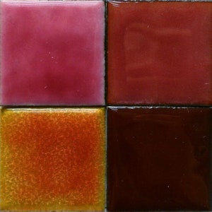 May include: Four square ceramic tiles with different colors and textures. The top left tile is a light pink, the top right tile is a dark red, the bottom left tile is a shiny orange, and the bottom right tile is a dark brown.