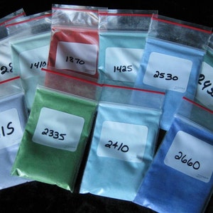 May include: Ten small plastic bags filled with different colored powders. The bags are labeled with numbers, including 2615, 2335, 2410, 2660, 2530, 2435, 1445, 1870, 1410, and 28.