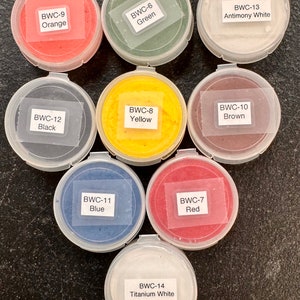 May include: Assortment of 14 small containers of paint powder in various colors, including orange, green, white, black, yellow, brown, blue, red, and titanium white. Each container has a label with the color name and a code, such as "BWC-9 Orange".