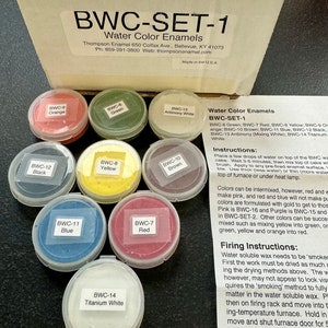 May include: A set of 14 water-soluble enamel paints in small containers, labeled with color names and BWC codes. The set includes colors like red, green, blue, yellow, orange, brown, black, and white. The box includes instructions for using the paints, including mixing and firing techniques.