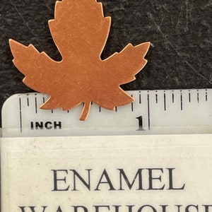 K&ouml;nnte beinhalten: Ein kupferner Ahornblattausschnitt mit einer L&auml;nge von knapp 2,5 cm. Das Blatt ist ein schlichtes Design mit einer glatten, leicht strukturierten Oberfl&auml;che.