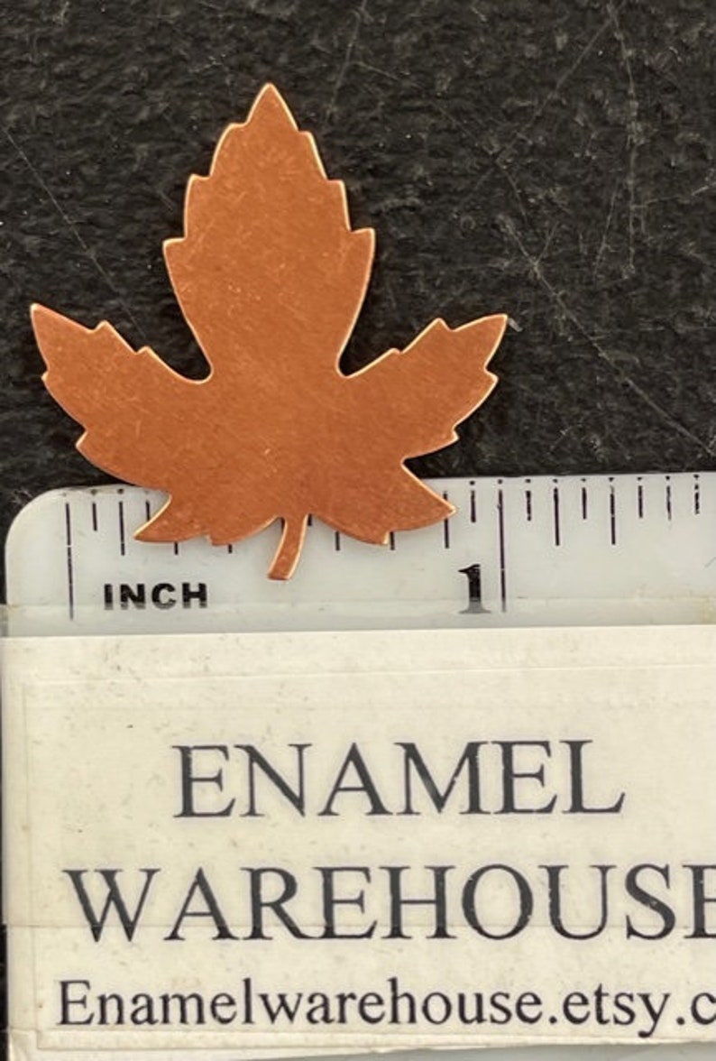 K&ouml;nnte beinhalten: Ein kupferner Ahornblattausschnitt mit einer L&auml;nge von knapp 2,5 cm. Das Blatt ist ein schlichtes Design mit einer glatten, leicht strukturierten Oberfl&auml;che.