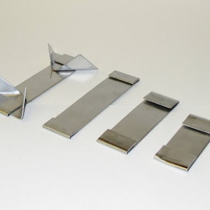 May include: Five silver metal clips, some with a folded design, for hanging items.
