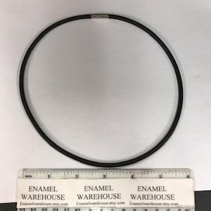 Könnte beinhalten: Eine schwarze Gummikette mit einem silbernen Verschluss. Die Kette ist 15 cm lang.