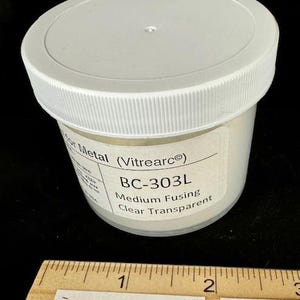 May include: A small white jar with a white lid labeled "BC-303L Medium Fusing Clear Transparent" for use with glass fusing projects. The jar is sitting on a wooden ruler with the text "Enamelwarehouse.etsy.com" printed on it.