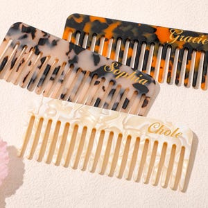 May include: Three personalized combs in the image. One is tortoiseshell with the name "Gracie" in gold. Another is a cream and black pattern with "Sophia". The third is cream with "Chole".