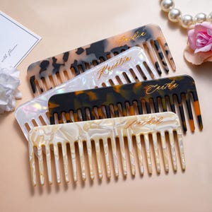 May include: Four rectangular hair combs with wide teeth, each featuring a unique marbled or tortoiseshell pattern in shades of brown, black, white, and iridescent pearl. Each comb is personalised with a gold cursive name: Amelie, Kristin, Eartha, and Rachel.