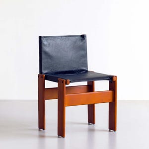 May include: A mid-century modern chair with a dark blue leather seat and backrest. The chair has a wooden frame with a warm, orange-brown finish. The design features a simple, geometric form, showcasing a blend of functionality and style.