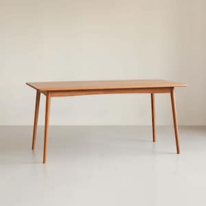 May include: A rectangular wooden table with a light brown finish. The table has four slender, angled legs and a simple, minimalist design. The table measures approximately 60 inches long.