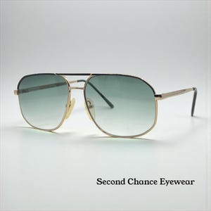 Könnte beinhalten: Goldfarbene Pilotenbrille mit grün verlaufenden Gläsern. Die Brille hat einen Doppelsteg und ein klassisches Design. Der Text "Second Chance Eyewear" ist unten im Bild aufgedruckt.