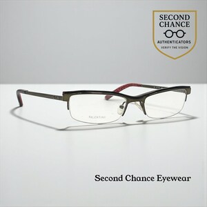 May include: Valentino spectacles with a dark grey frame and a half-rim design. The temples have a red and black pattern. The lenses are clear, and the brand name is visible on the lens. The image also includes the text "Second Chance Eyewear".