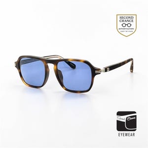 Puede incluir: Gafas de sol con montura carey y lentes azules. Las monturas cuadradas tienen un diseño clásico con un acento metálico en las patillas. La imagen incluye el texto "Second Chance Eyewear".