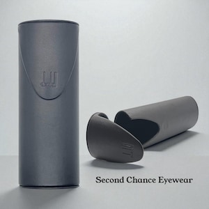 May include: A dark gray cylindrical eyeglasses case with a matching lid, open to the side. The case has a curved design and the brand name "dunhill" is visible. The text "Second Chance Eyewear" is at the bottom.