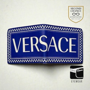 Może przedstawiać: Niebieski portfel Versace z białym napisem i szachownicowym obramowaniem. Portfel ma dwukrotnie składaną konstrukcję, a nazwa marki jest wyraźnie widoczna. Obraz zawiera również logo autentykacji "Second Chance".