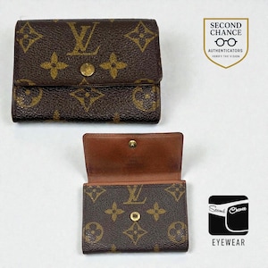 May include: Brown and tan wallet featuring a repeating pattern of interlocking "L" and floral designs. The wallet is shown closed and open, revealing a brown interior. A gold-coloured snap closure is visible. The wallet is a vintage item.