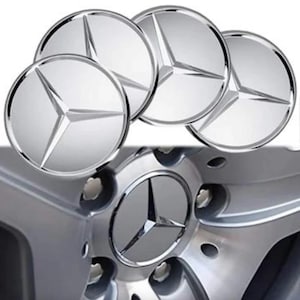 May include: Four silver hubcaps with the Mercedes-Benz logo, a three-pointed star within a circle. The hubcaps are displayed above a silver car wheel with a matching logo in the center.