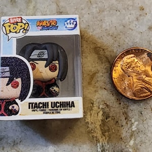 May include: A Funko Pop! vinyl figure of Itachi Uchiha from the Naruto Shippuden anime series. The figure is in a clear plastic display case. A penny is next to the figure for size comparison. The figure has black hair and red eyes.