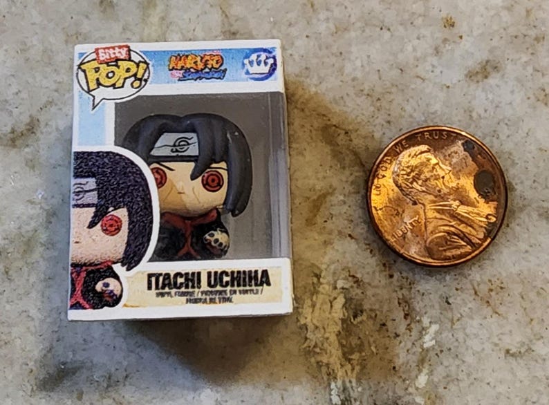 May include: A Funko Pop! vinyl figure of Itachi Uchiha from the Naruto Shippuden anime series. The figure is in a clear plastic display case. A penny is next to the figure for size comparison. The figure has black hair and red eyes.