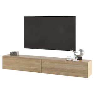 Peut inclure: Un meuble TV flottant moderne en bois clair. Il comporte deux tiroirs et est orné d'objets décoratifs, dont une petite boîte, une sculpture et deux verres transparents. Un grand écran plat noir est monté au-dessus de l'unité.