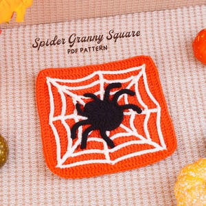 May include: A square crochet piece featuring an orange background with a white web pattern and a black spider in the center. The text Spider Granny Square PDF PATTERN is printed above the crochet piece, surrounded by small decorative pumpkins.