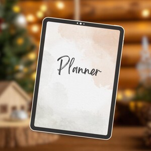 Könnte beinhalten: Ein digitaler Planer mit schwarzem Rahmen. Der Bildschirm zeigt das Wort "Planner" in Schreibschrift vor einem Aquarell-Hintergrund in Pfirsich- und Beigetönen. Der Hintergrund ist unscharf, wodurch der Planer hervorgehoben wird.