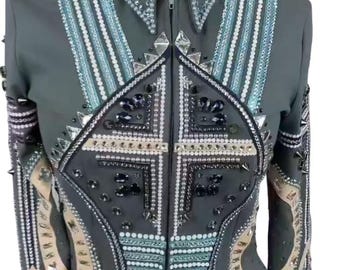 May include: Gray equestrian show jacket with intricate embellishments. Features a zip-up front, a structured collar, and decorative patterns with silver, blue, and black accents. The text "HIDE HAVEN SADDLERY" is displayed on the collar.