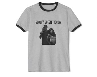 May include: A grey ringer t-shirt with black trim. The shirt displays a black and white image of two people and the text "SCOTTY DOESN'T KNOW" in a distressed font.