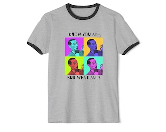 May include: A grey ringer t-shirt with a black trim. The shirt displays a pop art design of a man in four coloured squares, with the text "I KNOW YOU ARE, BUT WHAT AM I?"