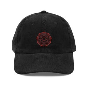 May include: Black corduroy baseball cap with a red geometric design embroidered on the front. The cap has a curved brim and an adjustable strap at the back. A stylish accessory for casual wear.
