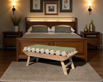 May include: A bedroom scene featuring a wooden bed, nightstands, and a bench with a green and cream patterned cushion. The room is decorated with framed botanical prints and sconce lighting, creating a warm and inviting atmosphere.