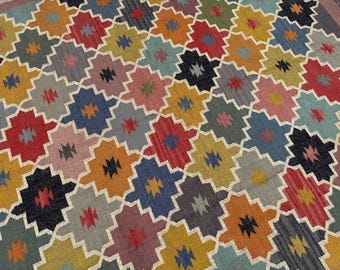 May include: A colorful, patterned rug with a repeating geometric design. The rug features a variety of colors, including red, blue, yellow, orange, and gray. The design is made up of interlocking shapes, creating a visually appealing pattern.