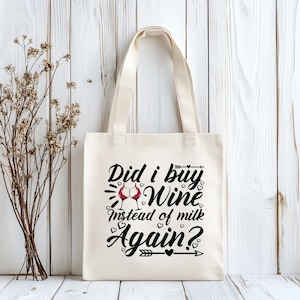 May include: Cream-colored tote bag with the text "Did I buy Wine Instead of milk Again?" in black script. The design includes two wine glasses and heart accents. The bag has two handles.