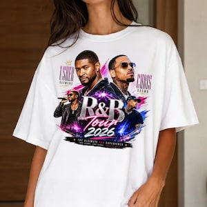 May include: A white short-sleeve t-shirt featuring a graphic print of Usher and Chris Brown. The design includes the text "Usher Raymond", "Chris Brown", "R&B Tour 2026", and "The Ultimate R&B Experience" with colorful pink and blue brushstroke accents.