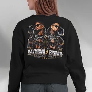 Back view of a black sweatshirt showing the contrasting bright metallic chrome and vibrant colors of the Raymond and Brown R&B Tour 2026 digital print file on dark garments.