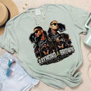 Summer lifestyle flat lay mockup featuring a light mint green t-shirt with the Raymond and Brown 2026 Tour PNG design, styled with denim shorts, sunglasses, and a straw hat.