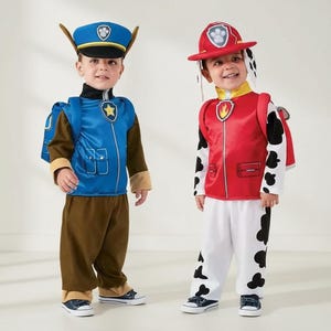 Könnte beinhalten: Zwei Kinder in Paw Patrol-Kostümen. Eines trägt als Chase eine blaue Polizeimütze und Uniform. Das andere ist als Marshall verkleidet, mit roter Feuerwehrkappe und Uniform mit schwarzen Flecken.