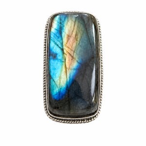 May include: A rectangular silver ring with a large labradorite stone. The stone has a shimmering display of colour, including blue, yellow, and orange. The ring has a detailed, rope-like border.