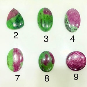 Pode incluir: Dez pedras preciosas polidas com cores verdes e magenta. As pedras estão numeradas de 1 a 10. As formas variam de ovais a lágrimas, com um acabamento liso e brilhante. Estas pedras são provavelmente usadas para joias ou fins decorativos.