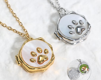 May include: Two necklaces with paw print pendants. One pendant is gold-toned with a gold paw print, and the other is silver-toned with a silver paw print. The pendants open to reveal a space for a small photo.