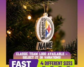 May include: A white circular Christmas ornament featuring the Pittsburgh Steelers logo with a football texture on the left side and the word NAME in black block letters at the bottom, hanging from a gold string on a green pine tree branch.