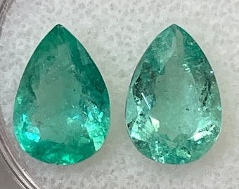 Puede incluir: Dos piedras preciosas de esmeralda en forma de pera en un recipiente de plástico transparente. Las piedras preciosas son de un color verde vibrante y tienen un acabado liso y pulido.