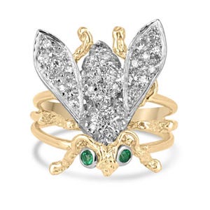 May include: A gold ring with a diamond-encrusted bee design. The bee has emerald green eyes and is set on a twisted band.