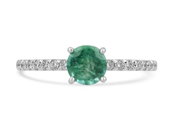 May include: A silver ring featuring a round green emerald gemstone set in a band of small diamonds.
