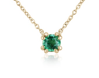May include: A delicate gold chain necklace with a small, round emerald green gemstone pendant.