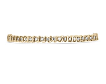 May include: A gold tennis bracelet with a row of small round diamonds.